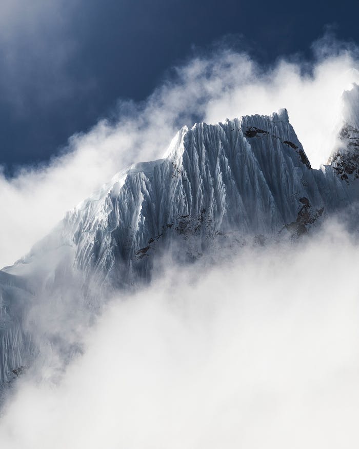 services-01 Breathtaking view of a snow-capped mountain peak rising through the misty clouds on a winter day.
