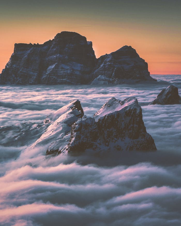 services-03 Captivating view of mountain peaks emerging through clouds at twilight, capturing nature's grandeur.